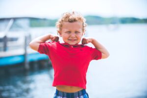 imagem site COCF sobre força disposição natural do ser humano criança blusa vermelha mostrando os musculos